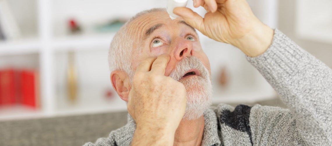 elderly person using eye drops