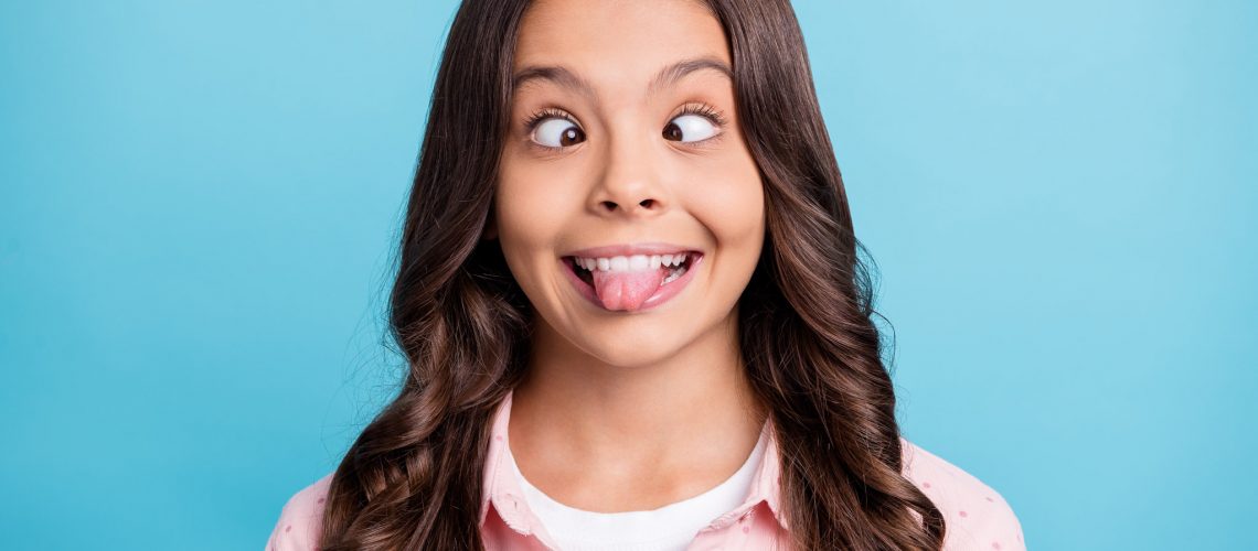 Portrait of carefree curly hairstyle school person show tongue squint eyes isolated on blue color background.